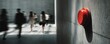 © Supardi - Red emergency button on concrete wall, blurred figures in background