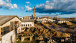 © AmazingAerialAgency - Aerial view of industrial buildings and lumber piles under a sky brushed with clouds, revealing the textures of the factory setting, Sremska Mitrovica, Vojvodina, Serbia.
