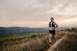 © aitor - Male endurance runner running along a narrow mountain trail surrounded by natural vegetation. Outdoor sports concept focused on trail running, adventure and fitness.
