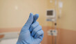 © Olia - Doctor hand in blue medical glove making finger heart gesture in hospital room background, healthcare compassion and patient support concept
