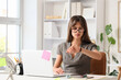 © Pixel-Shot - Young businesswoman with laptop checking time at her workspace in office. Deadline concept