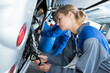© auremar - beautiful woman auto mechanic in blue overalls checks a bus