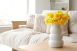 © Pixel-Shot - Vase with daffodils on table in light living room, closeup
