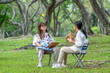 © BESTIMAGE - Two women are sitting in the park. One is painting and the other is holding a hat.