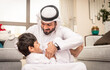 © oneinchpunch - Arab family wearing traditional emirati clothing bonding at home in Dubai
