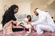© oneinchpunch - Arab family wearing traditional emirati clothing bonding at home in Dubai