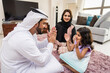 © oneinchpunch - Arab family wearing traditional emirati clothing bonding at home in Dubai