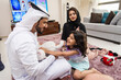 © oneinchpunch - Arab family wearing traditional emirati clothing bonding at home in Dubai