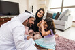 © oneinchpunch - Arab family wearing traditional emirati clothing bonding at home in Dubai