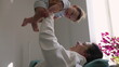 © Marco - Mother lifting baby in the air, joyful interaction, baby smiling, warm bonding moment, playful engagement, affectionate parent-child connection, carefree and loving family time