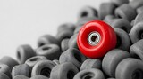 Single red skateboard wheel contrasts with pile of grey wheels