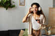 © LIGHTFIELD STUDIOS - Young woman enjoying music and a glass of wine in a cozy, stylish living room setting