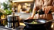 © mikhailberkut - Woman pouring olive oil into a frying pan with fresh broccoli. Healthy cooking in a modern kitchen. Meal preparation with organic ingredients