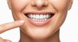 © Olga Ко - Extreme close-up of a woman pointing with one finger at perfect white teeth, dental care concept on pure white background.