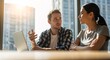 © Lynchsz - Two business colleagues discussing a project with a laptop on the table in a bright office space