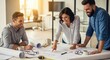 © twilight mist - Three smiling colleagues collaborate over detailed blueprints spread across a bright office desk