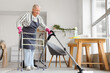 © Pixel-Shot - Mature woman with walker and vacuum cleaner cleaning floor at home