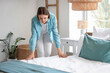 © Pixel-Shot - Beautiful young woman making bed in light bedroom