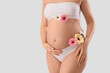 © Pixel-Shot - Young pregnant woman in underwear with gerbera flowers on white background, closeup