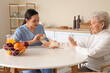 © Pixel-Shot - Physical therapist bandaging senior woman's arm in kitchen