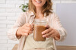 © Pixel-Shot - Young woman with jar mug of tasty iced latte at home, closeup