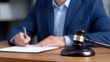 © Vasyl - Professional Lawyer Or Businessperson Signing An Important Legal Document On A Desk With A Justice Gavel Present
