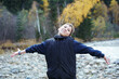 © Westend61 - Happy child with arms outstretched by river in autumn forest
