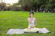 © leungchopan - Athletic woman doing breathing exercise in park