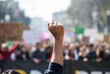 © Anastasiia - A raised fist amidst a protest crowd in an urban setting.
