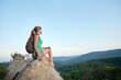 © bilanol - Lonely woman hiker sitting alone on rocky mountain top enjoying view of nature on wilderness trail. Active lifestyle concept