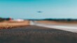 © LU - runway. A solitary airplane flying high in a clear blue sky above a softly focused airport runway. mobility guides, transit brochures, designed for mobility and urban transit guides.