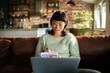 © Davor - Woman taking notes while working on laptop at home