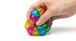 © Andrey - Colorful sensory ball being squeezed by a hand, isolated on a white background, showcasing vibrant textures and playful design