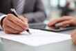 © Abu - Close-up of a persons hand signing a document with a pen, indicating a business transaction or agreement.