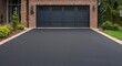© The 2R Artificiality - Asphalt driveway bordered by brick wall reaching a spacious garage door