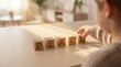 © Aisylu - Over the shoulder view of an child hand spelling the word peace with wooden alphabet blocks on a clean sunny desk featuring left copy space