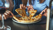 © Dragana Gordic - Friends Sharing Pizza Slices at a Cozy Restaurant Table Over Wine and Conversation