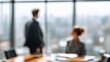 © Agung - Two professionals in a modern office meeting room with large windows.