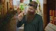 © Krakenimages.com - Caucasian young man with long beard pointing his index finger toward the sky in a narrow old town street, casual attire visible; thinking.