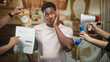 © Krakenimages.com - Black man rubbing cheek while alarm clock, document and megaphone are thrust toward him in studio; overwhelmed deadlines choices.