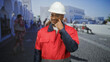© Krakenimages.com - Construction worker man in white hard hat and red uniform points finger to cheek while standing on a sunlit street with white buildings and pedestrians; pride duty.