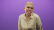 © Krakenimages.com - Woman sticks tongue out and makes silly face with hands while wearing glasses in purple studio; playful mischief.