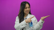 © Krakenimages.com - Young chinese woman scientist in uniform presenting with hand over isolated pink background wall.