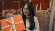 © Krakenimages.com - Woman smiling holding gift indoors at construction site with brick wall background, showcasing a cheerful moment amid industrial setting.