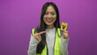 © Krakenimages.com - Young woman in reflective vest holding volunteer badge against isolated pink background showcasing volunteerism and readiness.