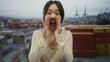 © Krakenimages.com - Woman calling out with hands cupped at seaside port with containers and cranes in background showcasing cheerful, young, chinese, woman enjoying outdoors.