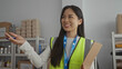 © Krakenimages.com - Woman in a reflective vest holds a clipboard in a charity volunteer center, surrounded by supplies and boxes, embodying a conscientious spirit in an indoor community setting.