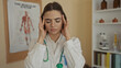 © Krakenimages.com - Doctor in uniform with stethoscope, woman looking stressed in clinic room with anatomical poster in background, suggesting a challenging workplace environment
