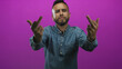 © Krakenimages.com - Man showing both middle fingers toward camera with rings and denim shirt in magenta studio; defiance attitude.