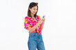 © sitthiphong - Portrait of young Asian woman in summer wearing floral shirt holding smartphone and smiling on white background.